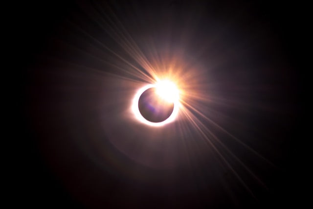 Solar eclipse with bright sunlight emerging behind the Moon